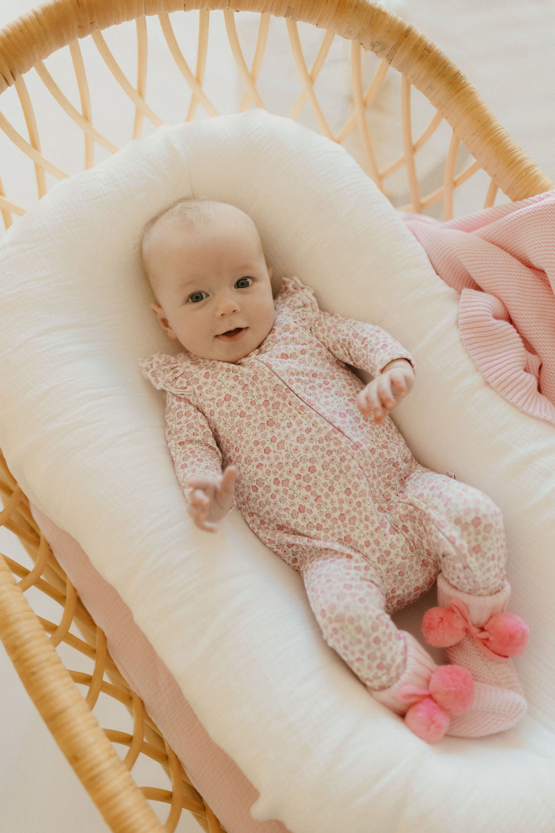 Baby wearing the Seashell Bloom Zipsuit, lying in a bassinet