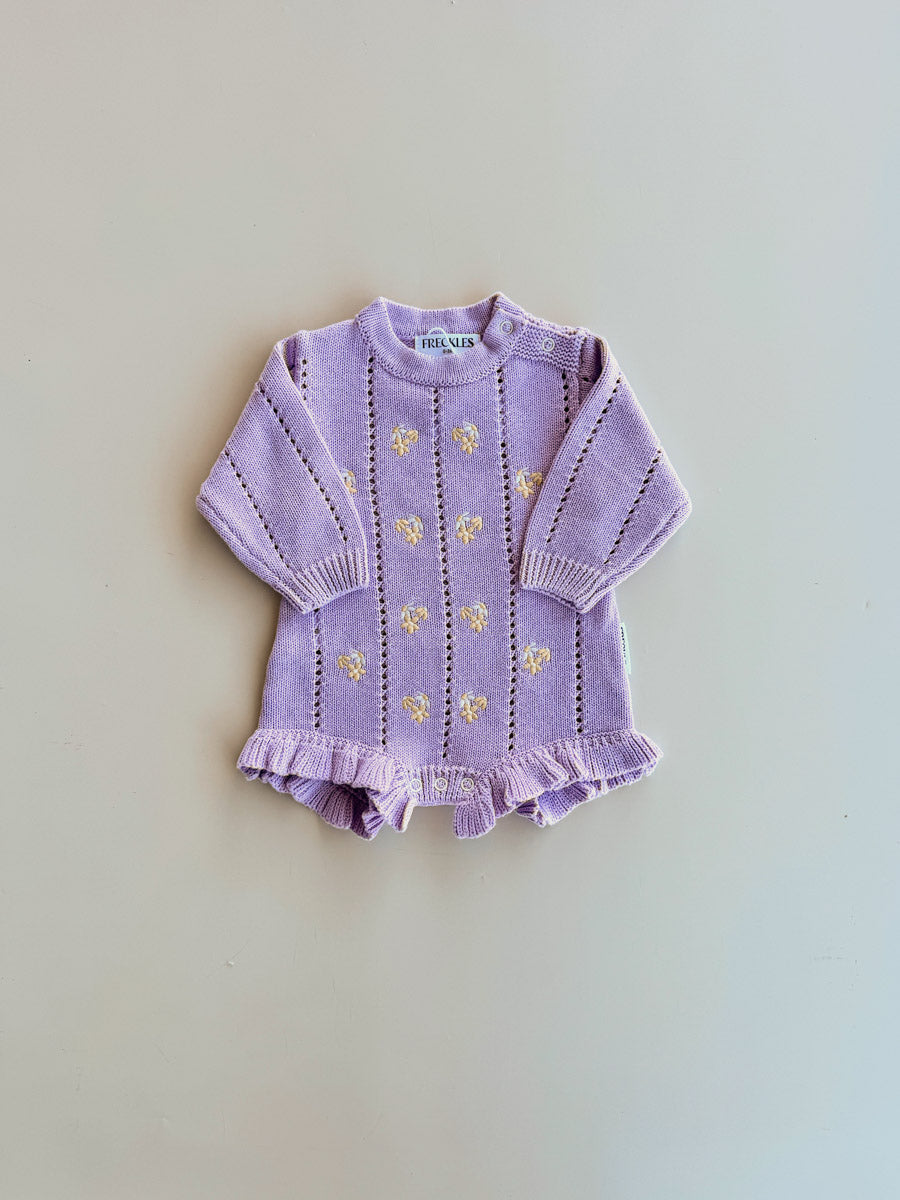 Freckles Bloom Pointelle LS Romper in Aster laid flat, with cream daisy embroidery and frilled legs