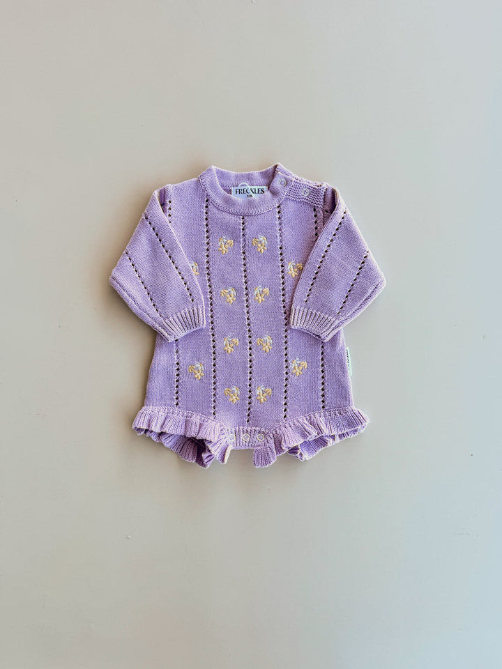 Freckles Bloom Pointelle LS Romper in Aster laid flat, with cream daisy embroidery and frilled legs