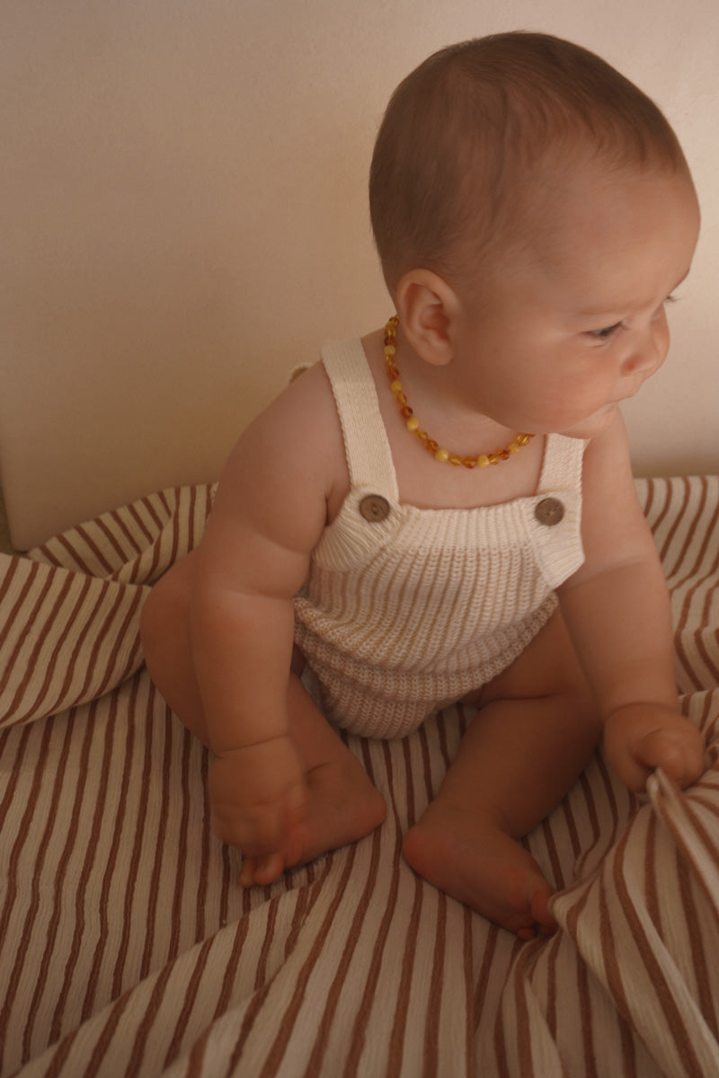 Baby wearing the Freckles The Label Chunky Button Romper in Oat, side view
