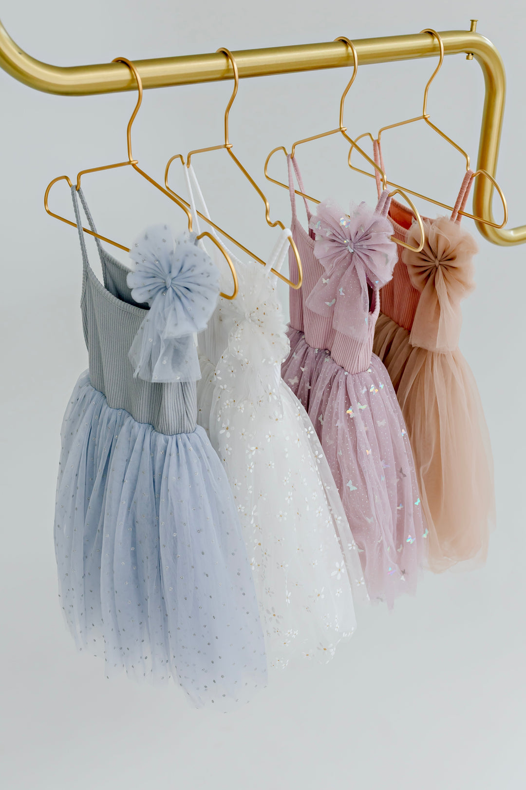 Confetti Kidz ribbed tulle dresses on a hanging rail, including Dusty Pink
