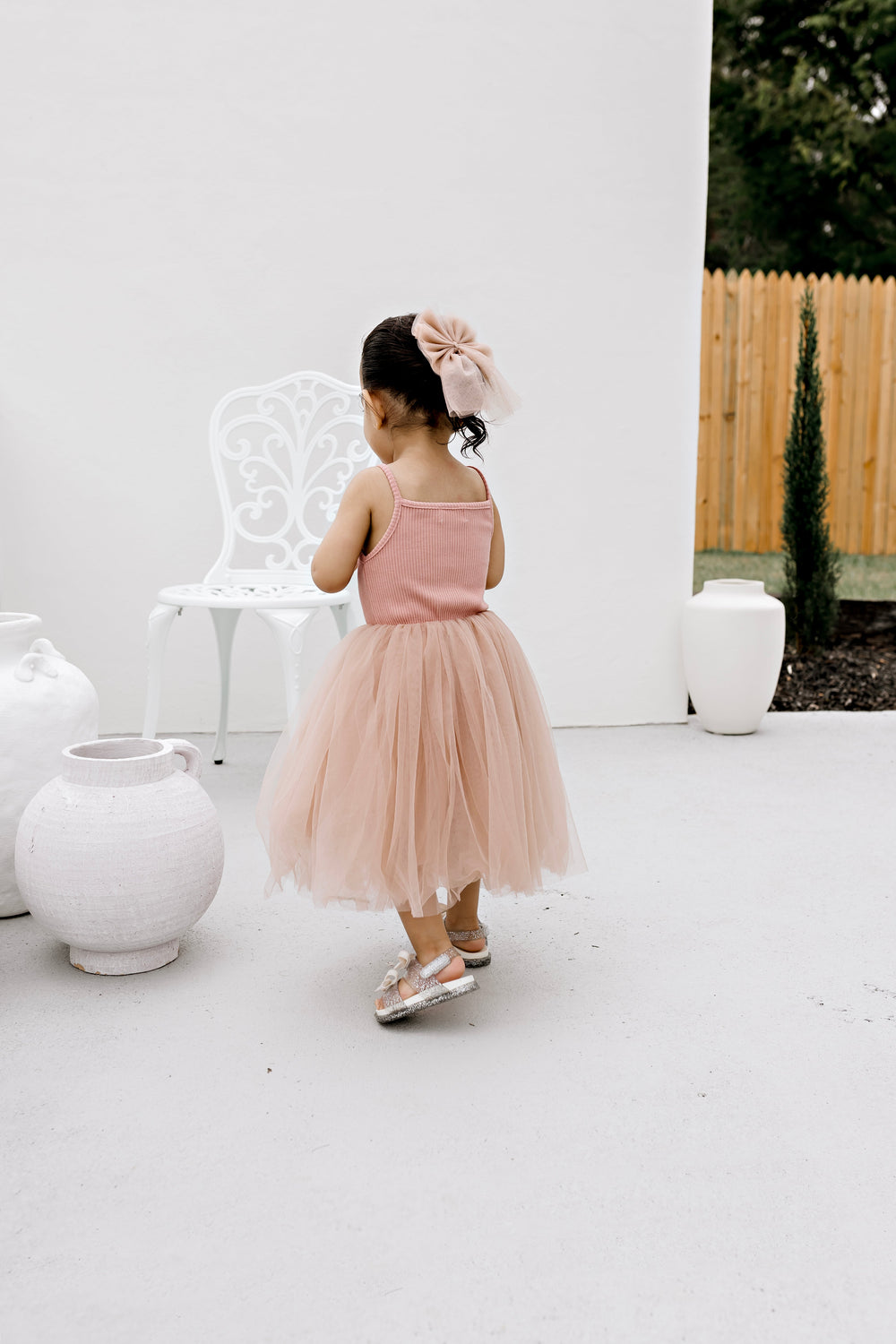 Girl wearing the Dusty Pink ribbed tulle dress, full length from behind
